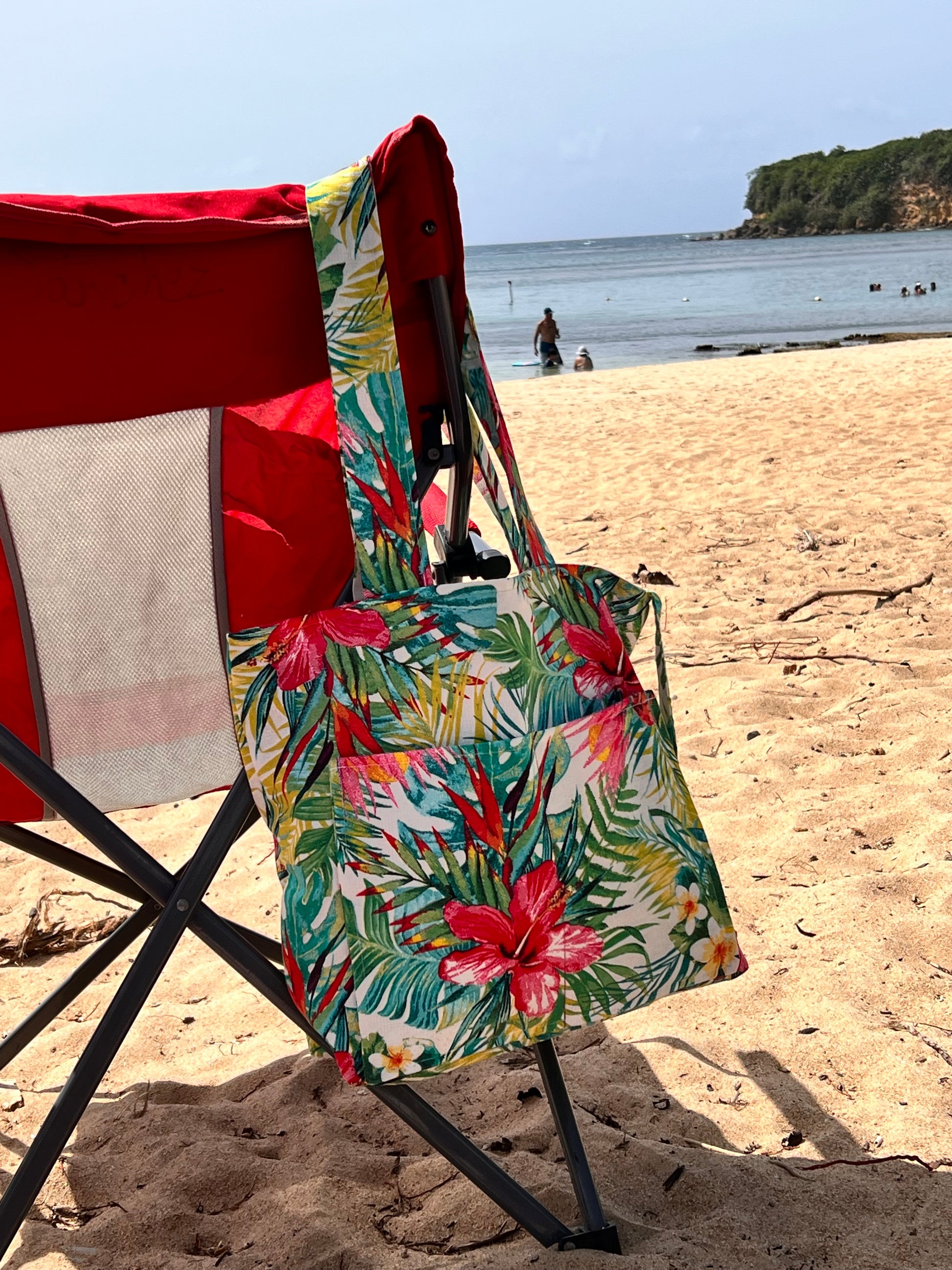 close view of red flowers and green leaves on beach tote