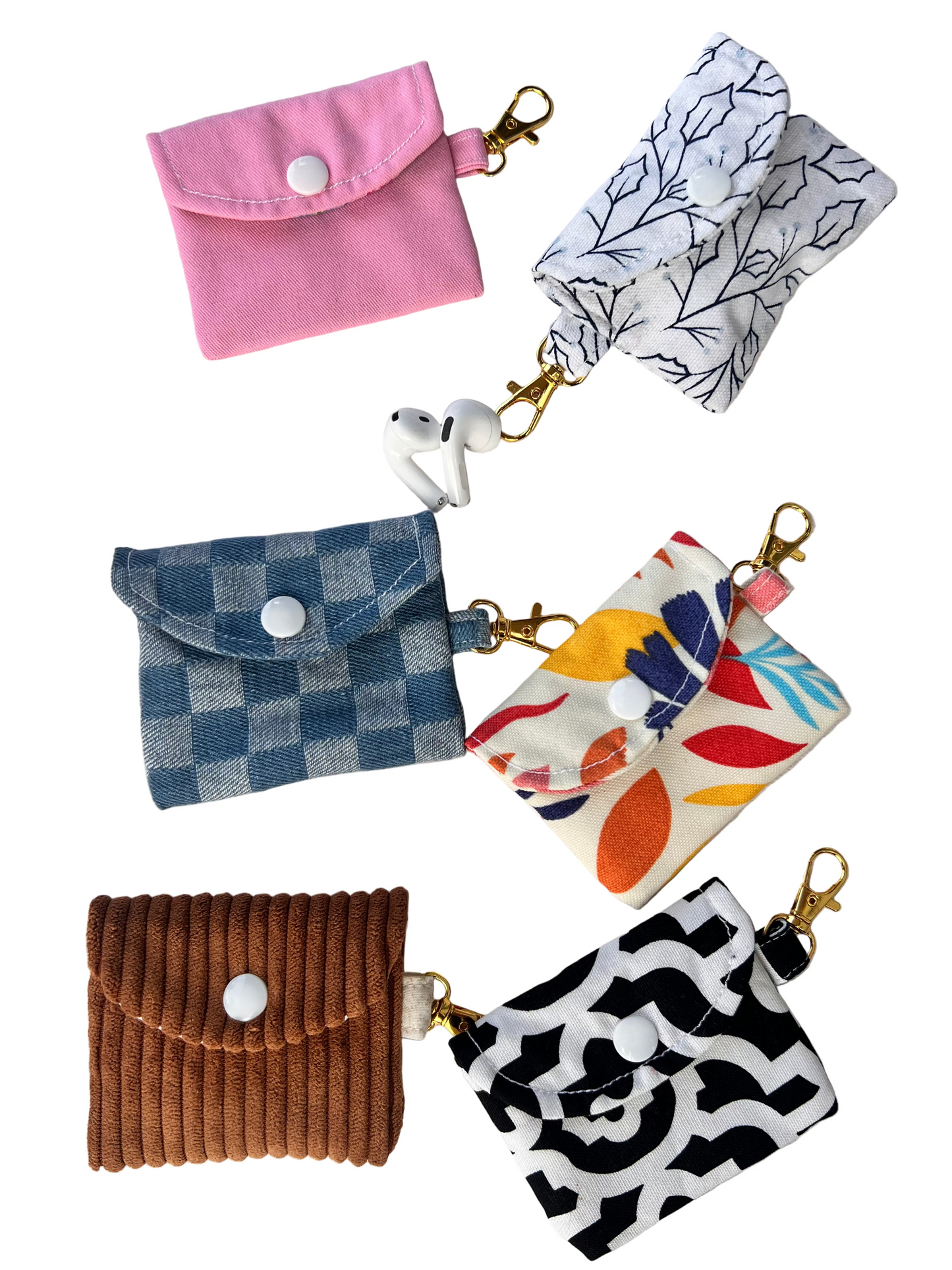 Collection of small fabric pouches with keychains on a light gray background